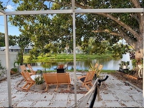 A covered patio with outdoor seating, a hammock, and a view of a lake and houses in the background. - Memories!! (Holiday)
