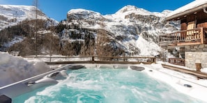 A hot spring area with a wooden deck and stone walls, surrounded by snow-covered mountains. - Chalet, wifi, 200m from ski slopes, Ground floor, view panoramic, terrace, balcony (Tignes)