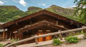 A wooden chalet with a sloped roof, a wooden fence in the foreground, and a mountainous backdrop. - Chalet, wifi, 200m from ski slopes, Ground floor, view panoramic, terrace, balcony (Tignes)