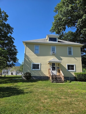 A two-story house with a front porch, a small staircase, and a garage. - Nice 5-bedroom renovated farmhouse,  with A-C, 1.6miles/5 min to beaches (South Haven)