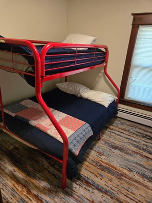 A bunk bed with a red frame, a patterned rug, and a window with blinds. - Nice 5-bedroom renovated farmhouse,  with A-C, 1.6miles/5 min to beaches (South Haven)