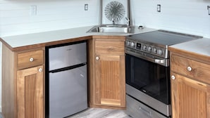 A kitchen with wooden cabinets, a stainless steel refrigerator, an oven, and a sink.