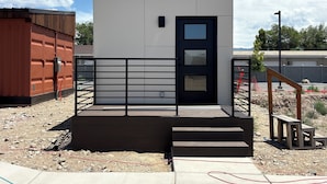 A modern building with a black door, a small window, and a metal railing.