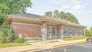 A brick building with a covered entrance, large windows, and a parking lot.