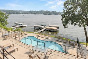 A pool area with lounge chairs and a view of the lake.