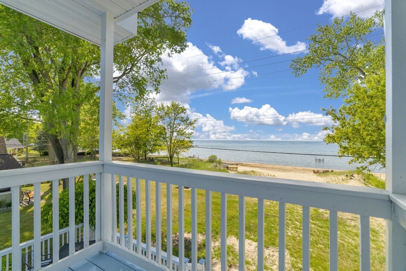 A covered porch with a view of a beach and ocean.