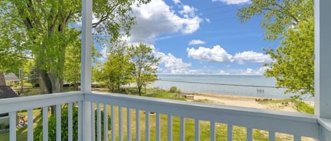 A covered porch with a view of a beach and ocean.