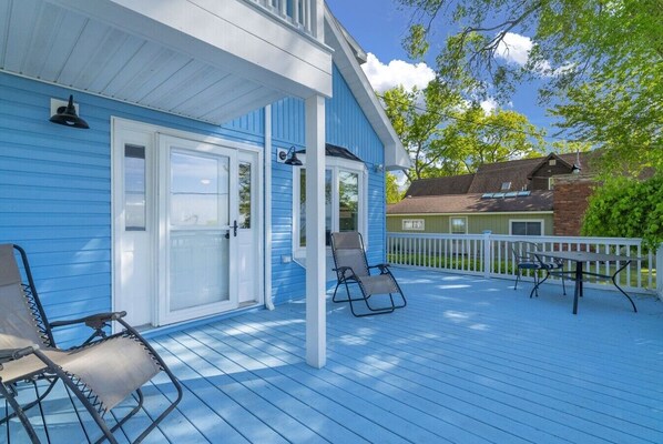 A blue house with a covered porch, two chairs, and a table.