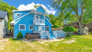 A two-story blue house with a balcony, a hot tub, and a fenced yard.
