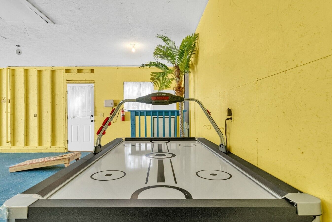 Une table de jeu de shuffleboard dans une pièce aux murs jaunes et au plafond blanc.
