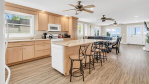 A modern kitchen with wooden cabinets, a central island with bar stools, and ceiling fans.