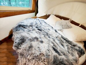 A cozy room with a bed, a window, and a view of trees.