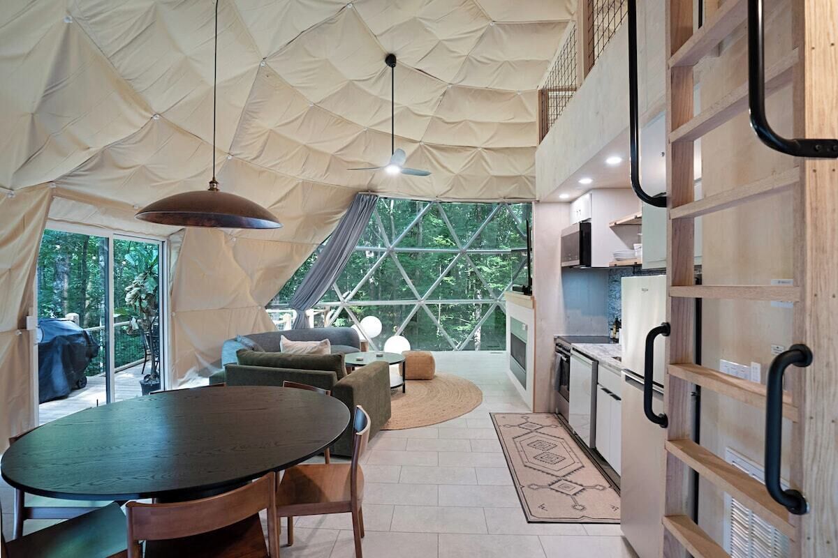 A tented accommodation with a dining area, kitchen, and seating space.