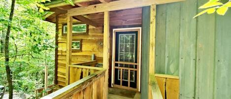 Een houten chalet met een veranda en een deur naar binnen.