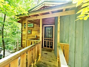 A wooden cabin with a porch and a door leading to the interior.
