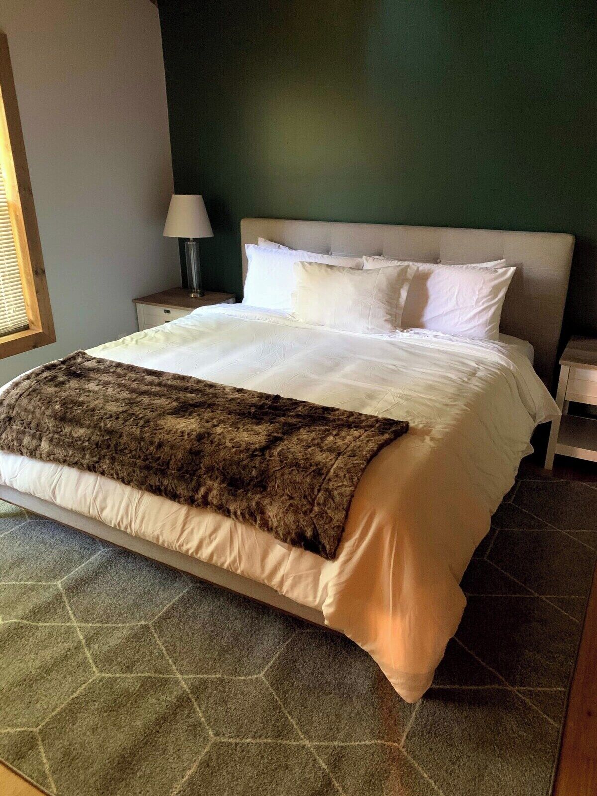 A bed with a white headboard, a brown throw blanket, and a matching pillow.