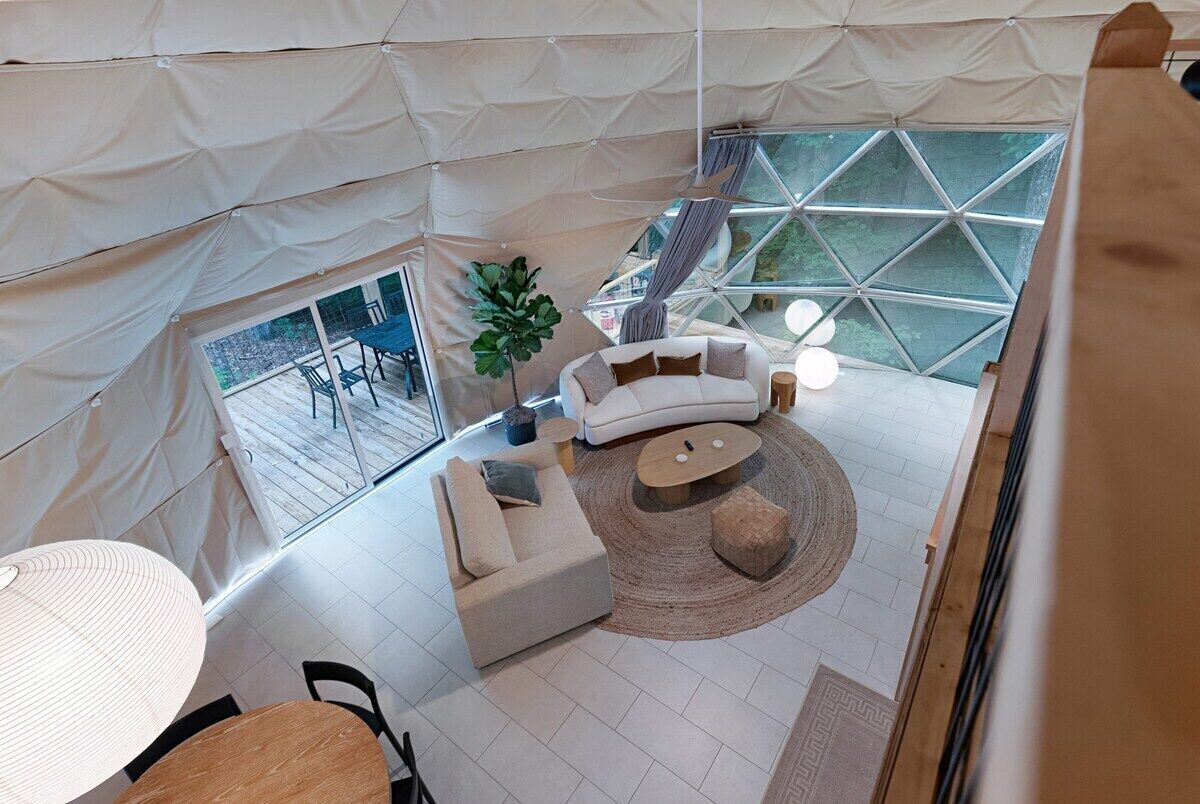 A tented room with a sofa, coffee table, and a large window.