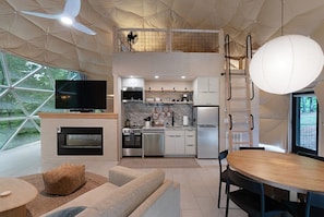 A modern kitchen with a TV, oven, and dining area.