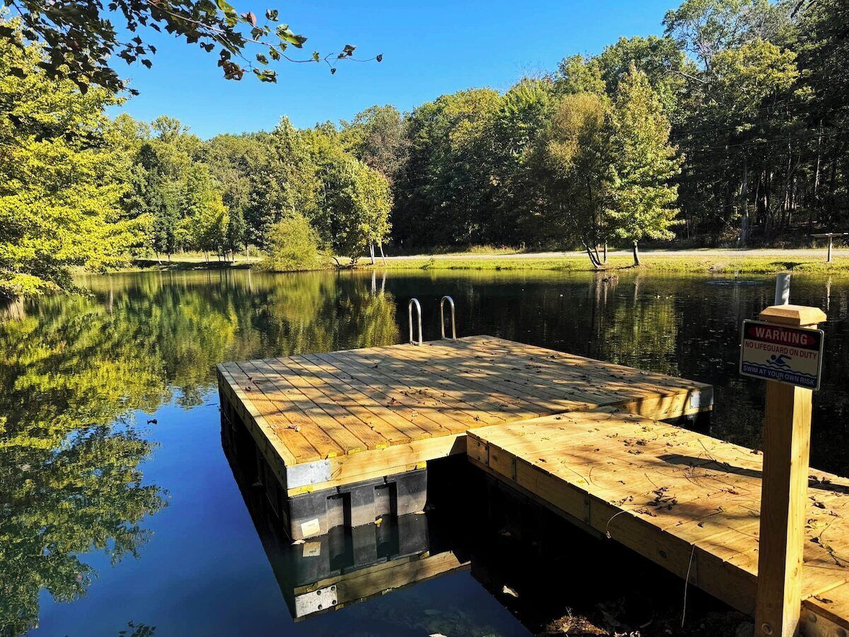 A wooden dock extending into a calm lake surrounded by trees.