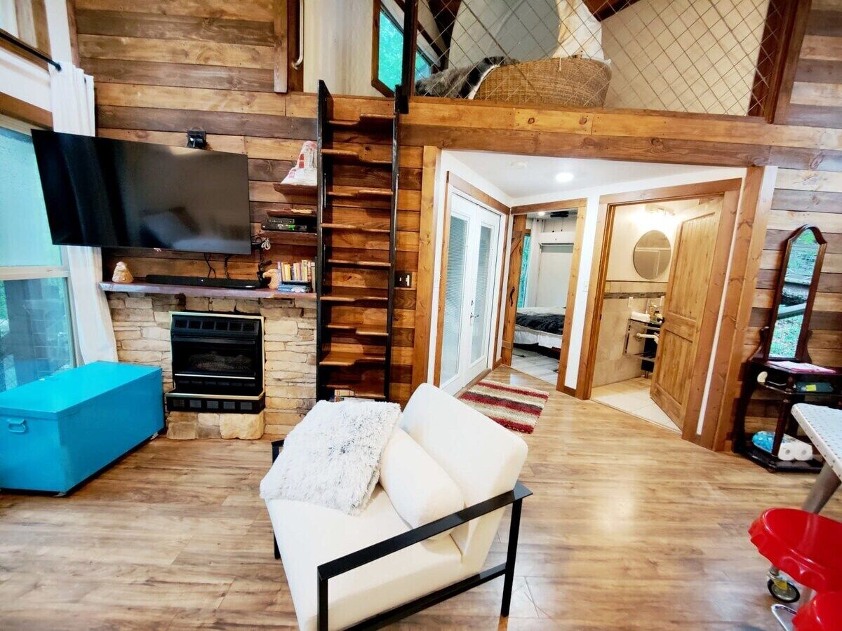 A cozy living room with a fireplace, a sofa, and a TV mounted on the wall.