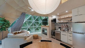 A modern kitchen with stainless steel appliances, a dining area with a wooden table, and a large window with a geometric view.
