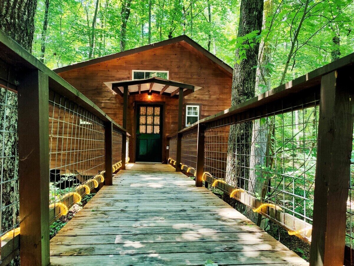 Une cabane en bois avec une allée couverte menant à l’entrée.