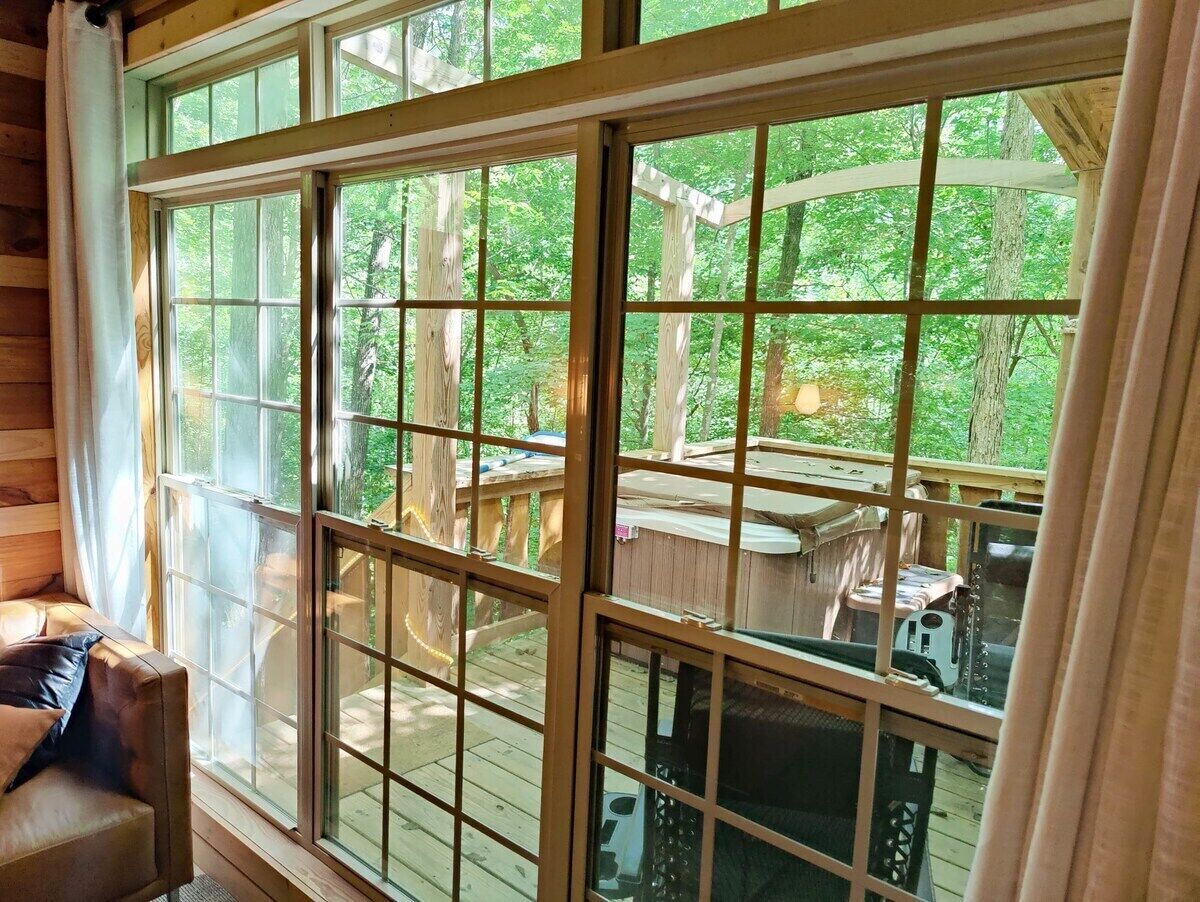 A cabin with large windows, a wooden deck, and a cozy seating area.