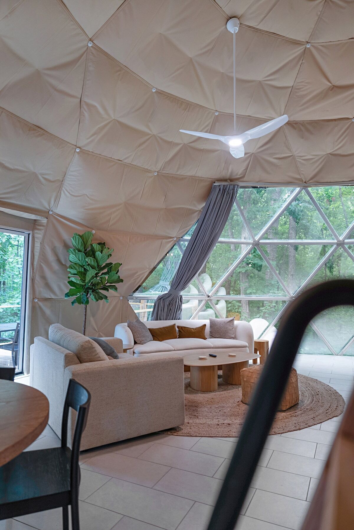 A tent-style room with a sofa, a dining table, and a ceiling fan.