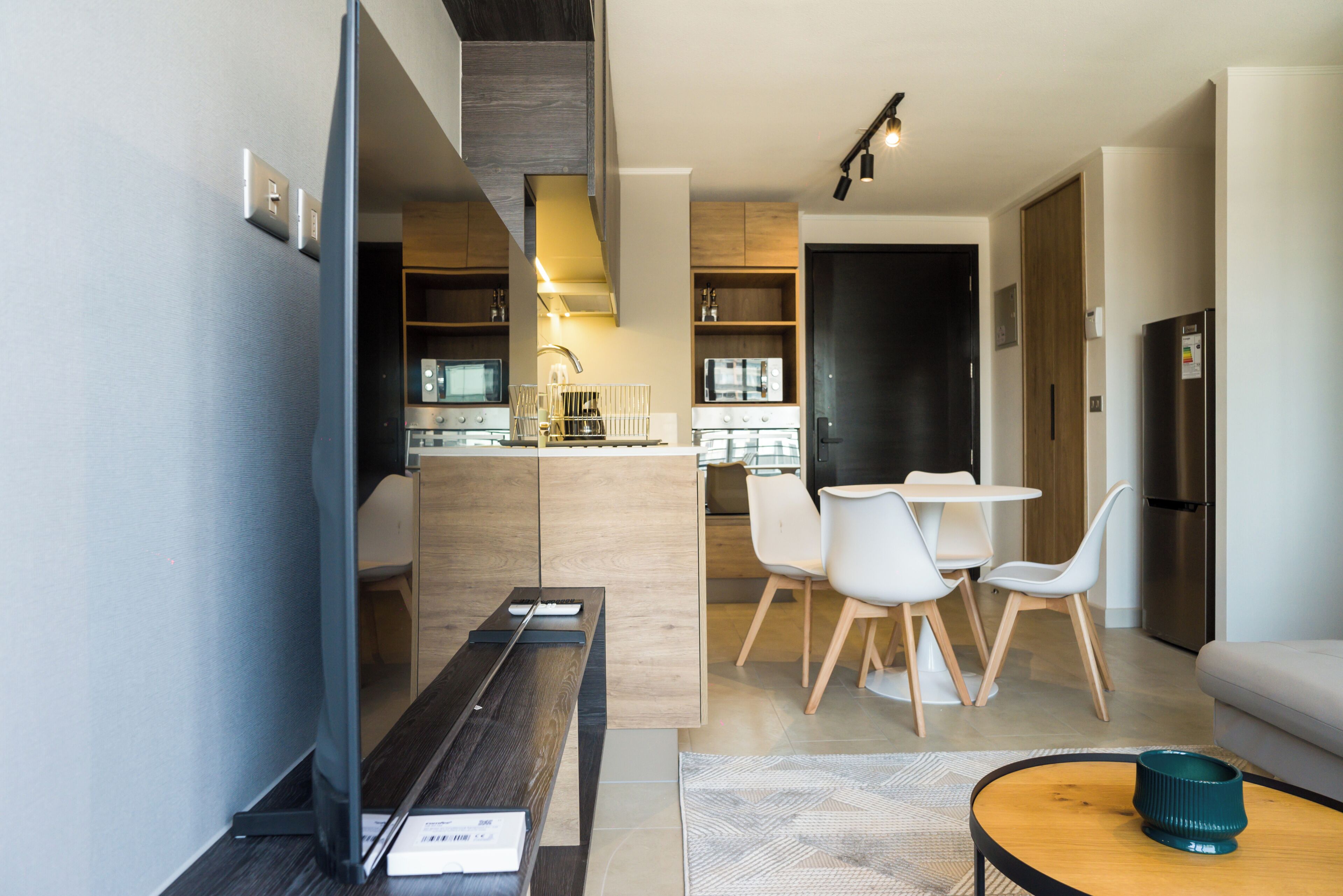 Una sala de estar moderna con un televisor de pantalla plana, una mesa de centro de madera y un sofá.