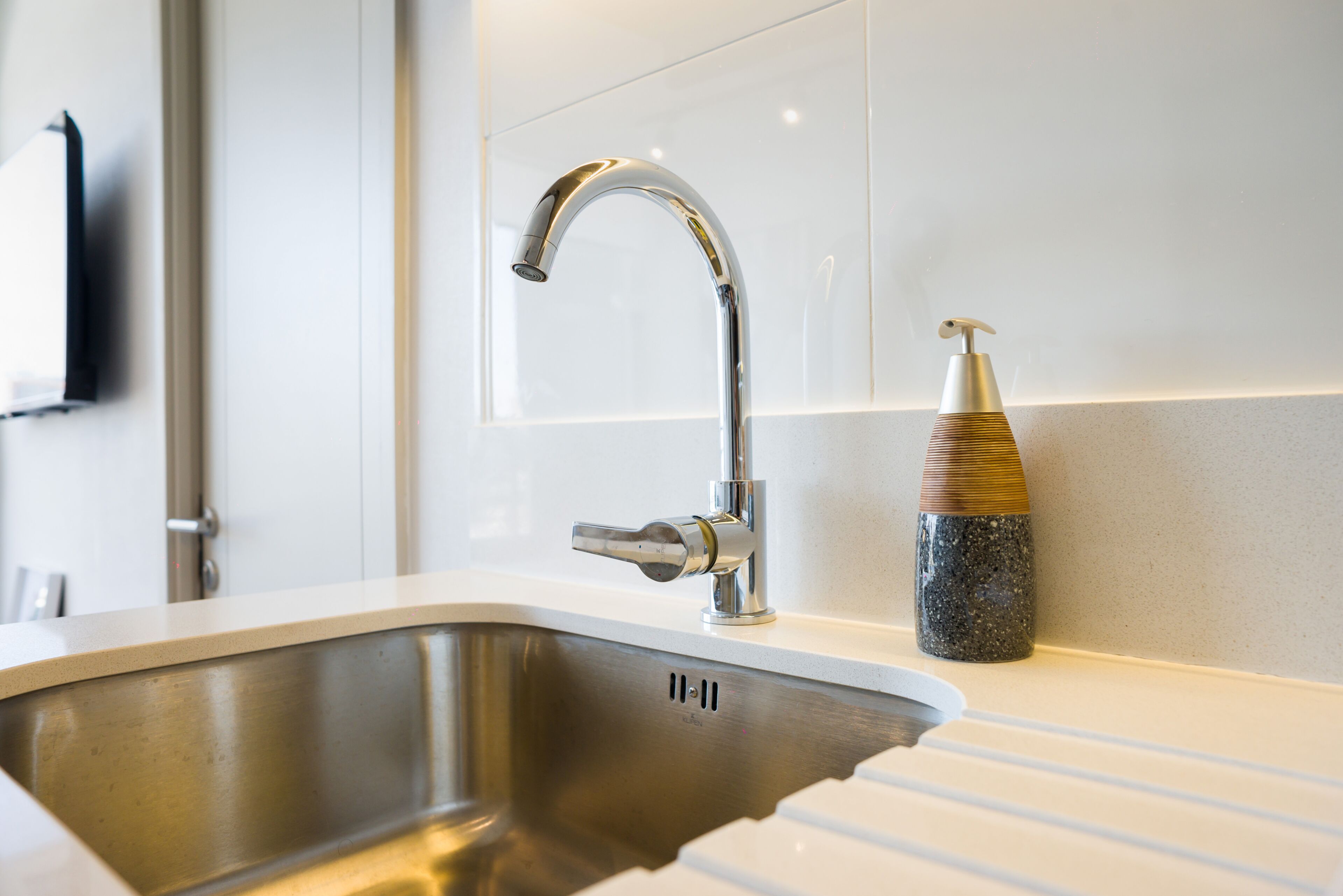 A modern kitchen with a stainless steel sink, a chrome faucet, and a soap dispenser.