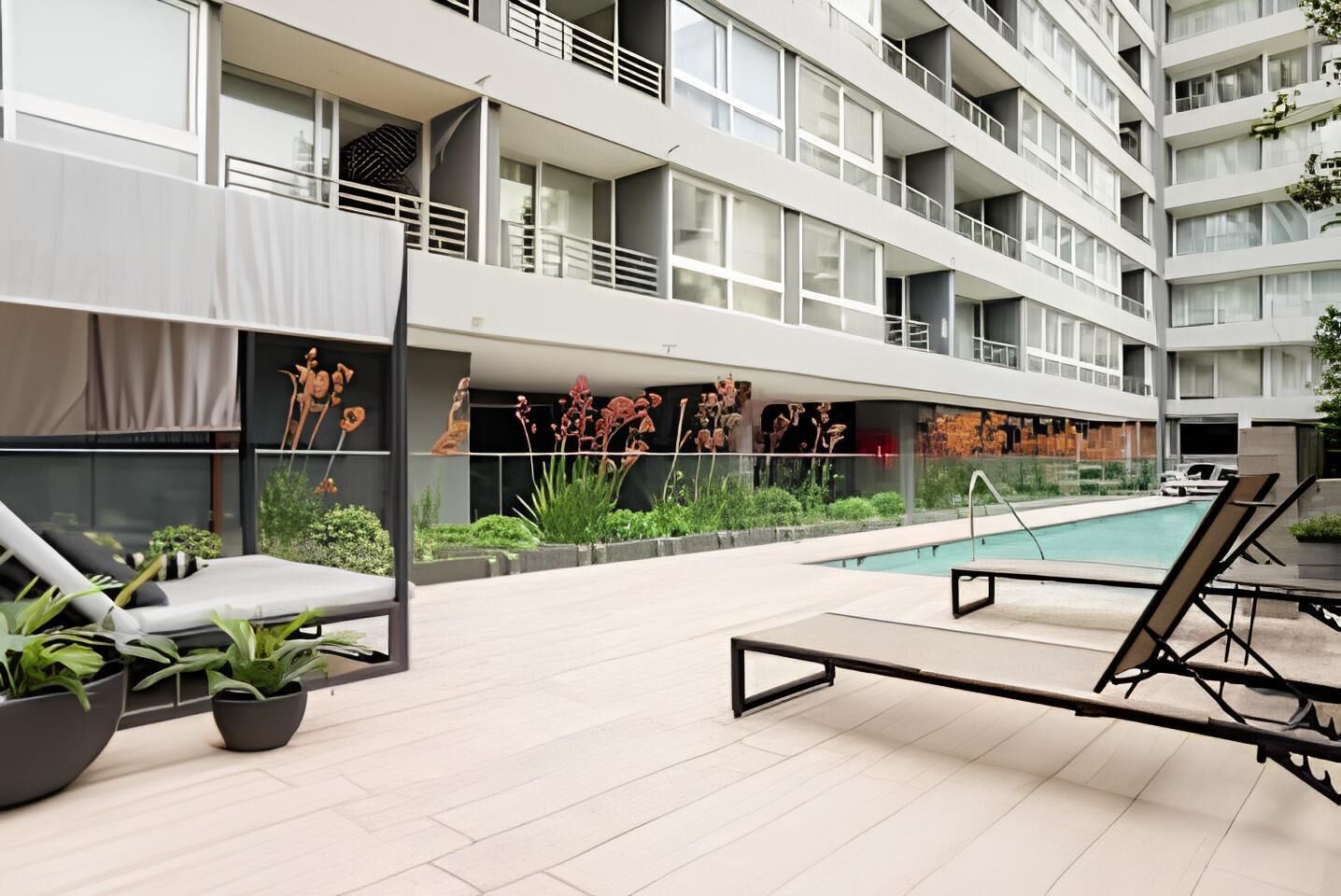 A modern building with a swimming pool, outdoor seating, and a mural.