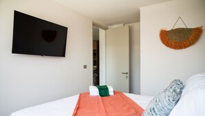 Habitación de hotel con una cama, un televisor de pantalla plana en la pared y una puerta que da a un baño.