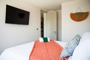 Ein Hotelzimmer mit einem Bett, einem an der Wand befestigten Flachbildfernseher und einer Tür zu einem Badezimmer.