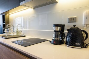 A modern kitchen with a coffee maker, a kettle, and a basket on the counter. - Vicuña Mackenna Apartments By Andes STR (Ñuñoa)
