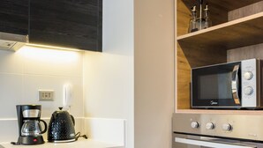 Una cocina moderna con armarios de madera, cafetera, hervidor y microondas.