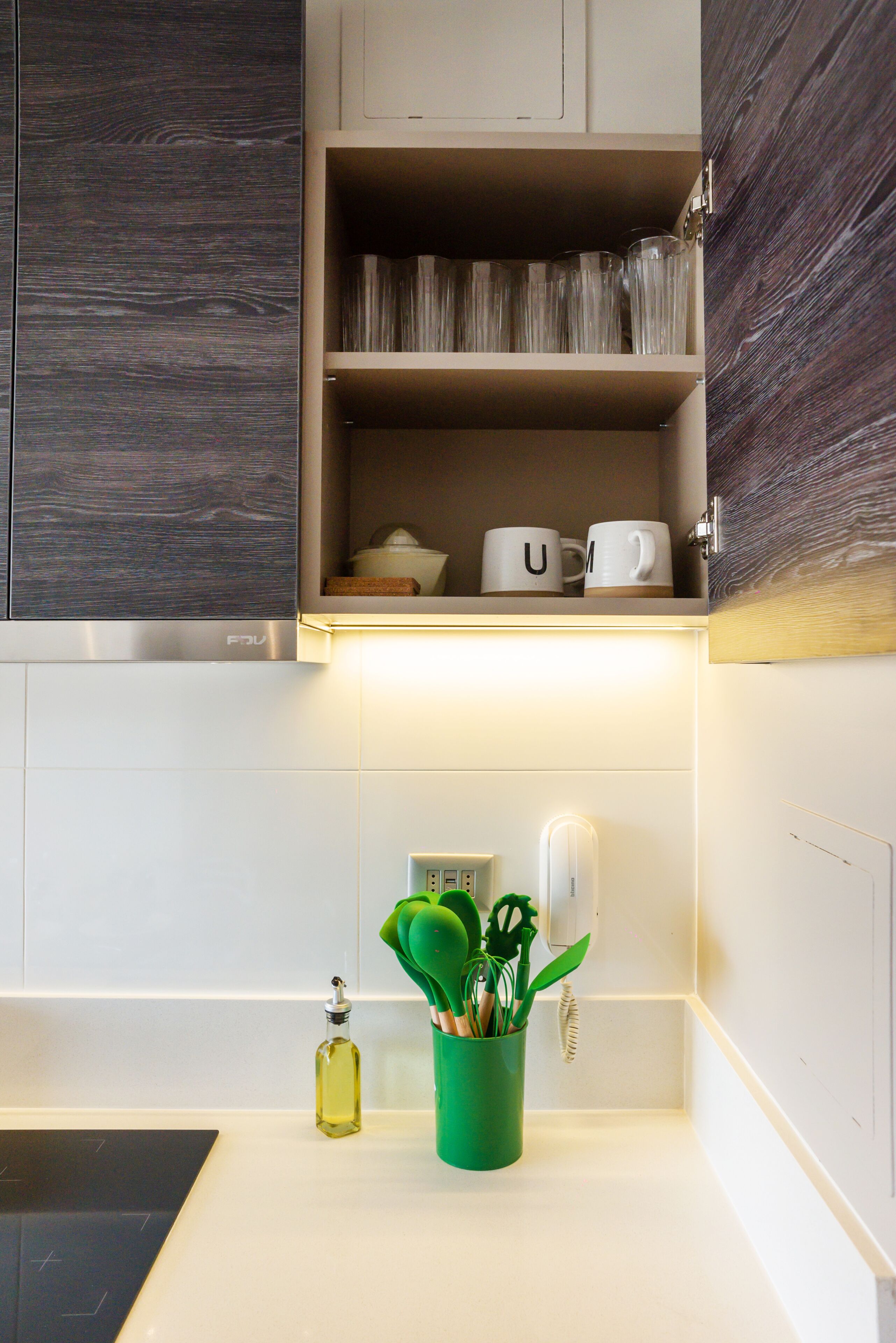 A kitchen with a built-in cabinet, a countertop, and a green utensil holder.