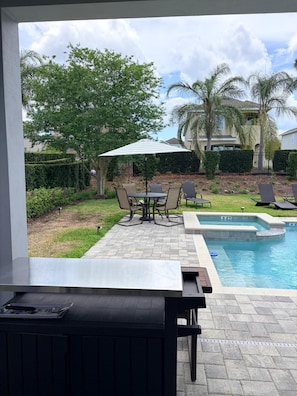 A patio area with a pool, outdoor furniture, and a view of a residential neighborhood. - Spacious 7-bedroom house near Disney World (Kissimmee)