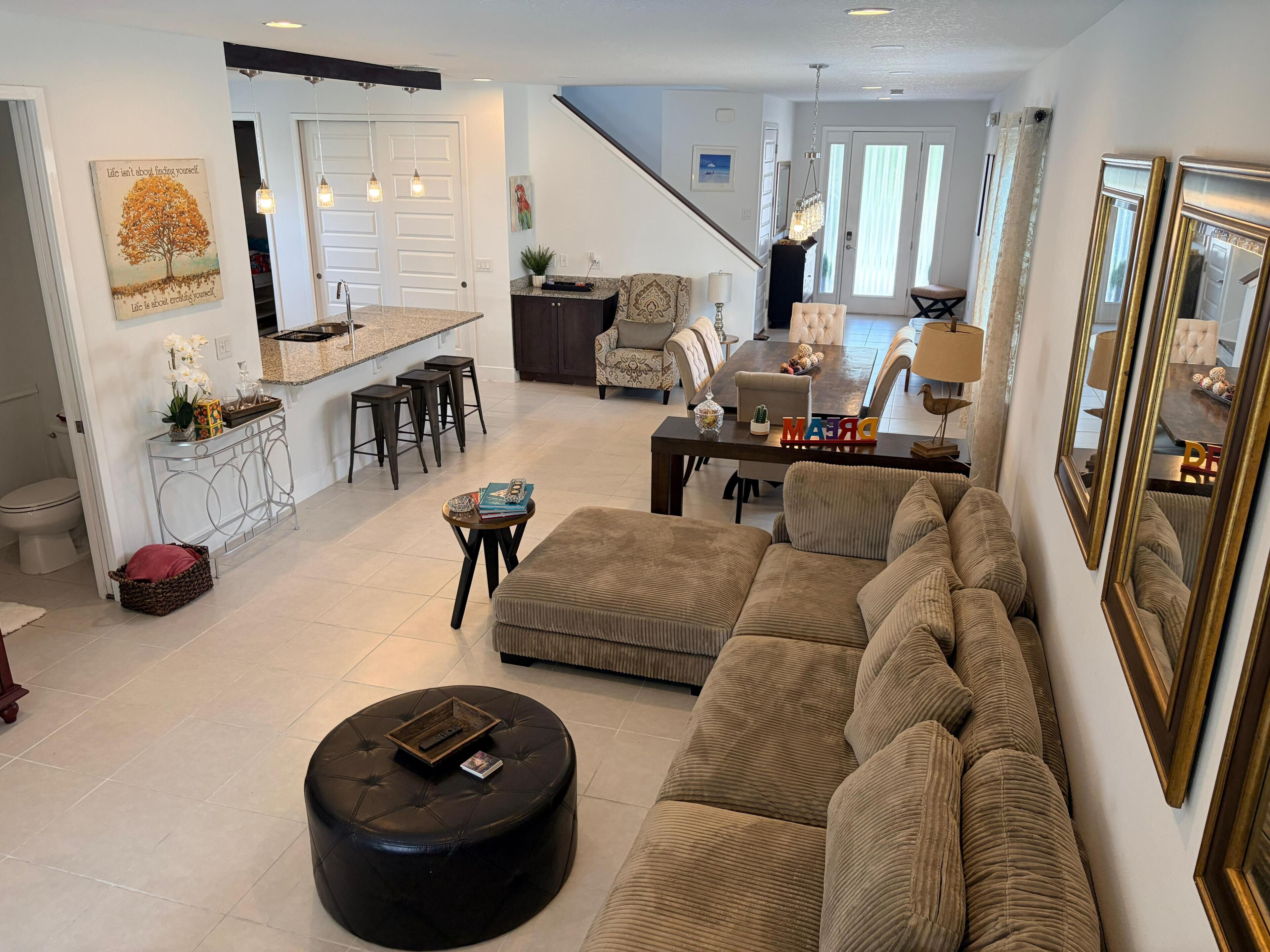 A spacious living area with a large sofa, ottoman, and a dining table.