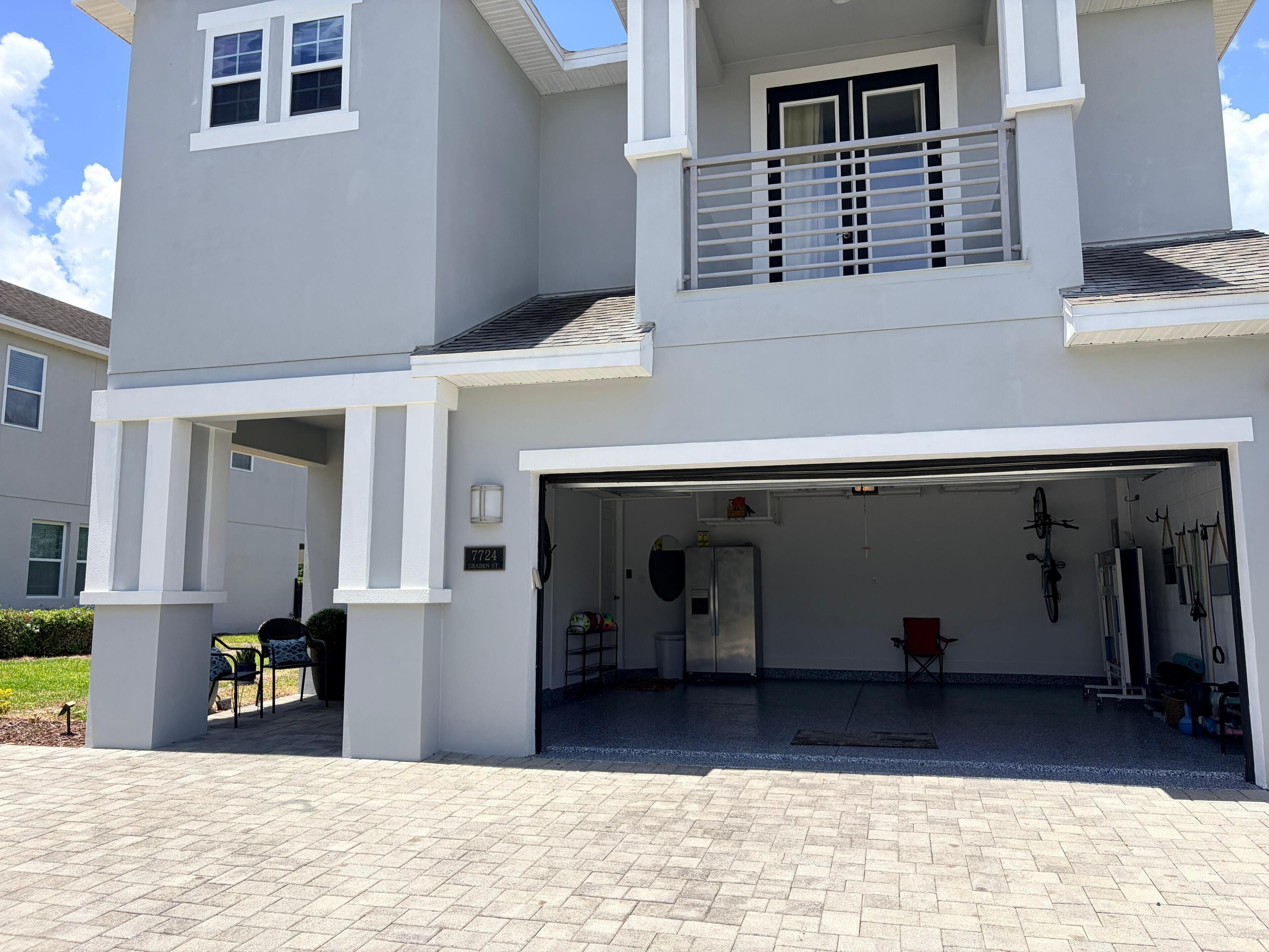 A two-story building with a garage entrance, a small outdoor seating area, and a bike rack.