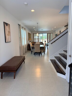 A spacious living area with a dining table, chairs, a bench, and a staircase. - Spacious 7-bedroom house near Disney World (Kissimmee)