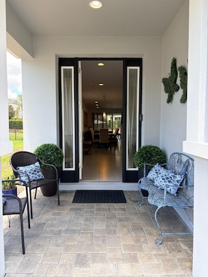 A covered outdoor area with a bench, potted plants, and a doorway leading to an interior space. - Spacious 7-bedroom house near Disney World (Kissimmee)