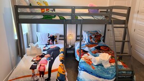 Ein Schlafraum mit Etagenbetten, wobei jedes Bett eine thematische Bettwäsche hat.