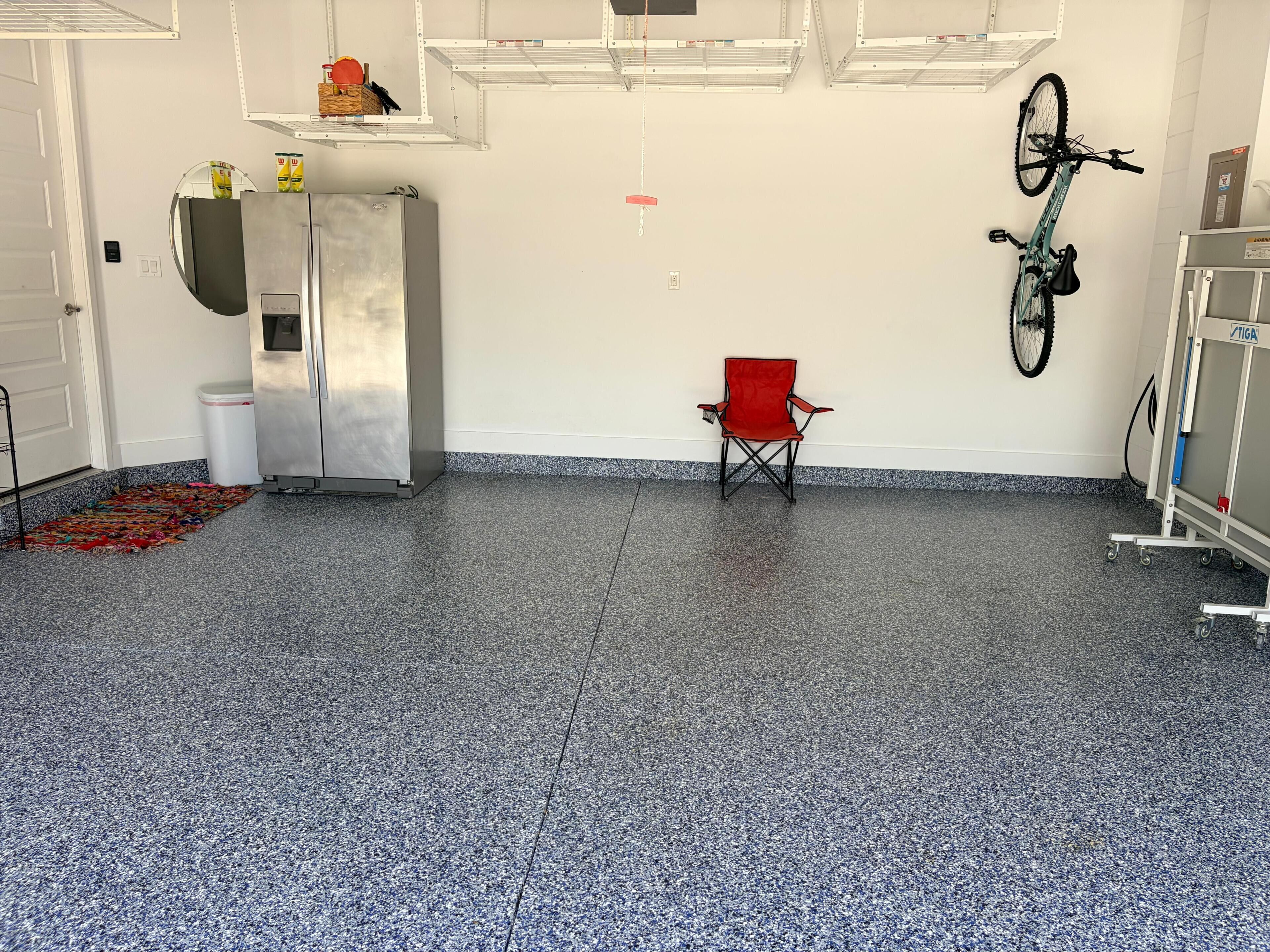 Una habitación con kitchenette, una silla plegable roja, una bicicleta y un carrito.