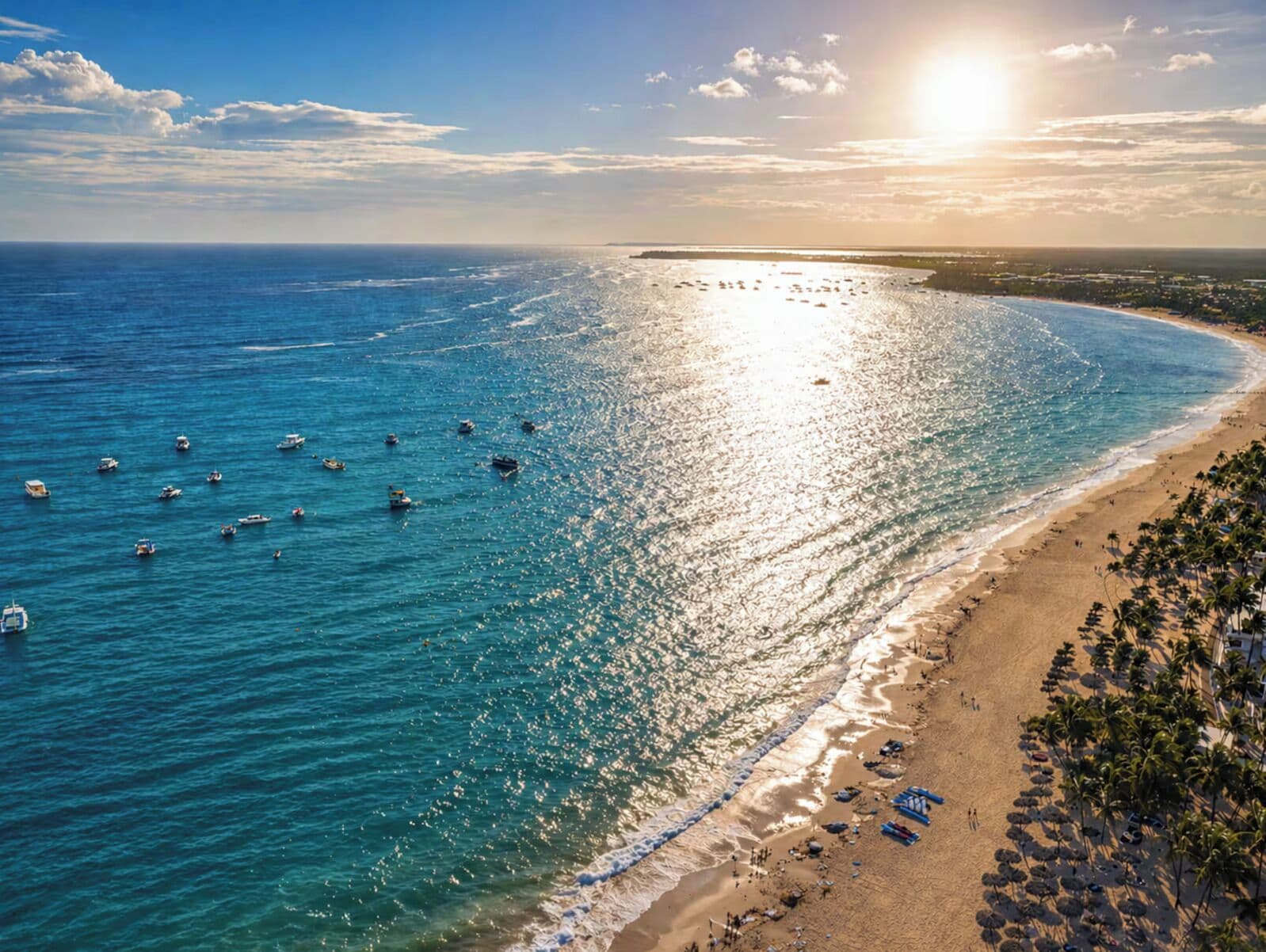 A beach with boats, a sandy shore, and a clear sky.