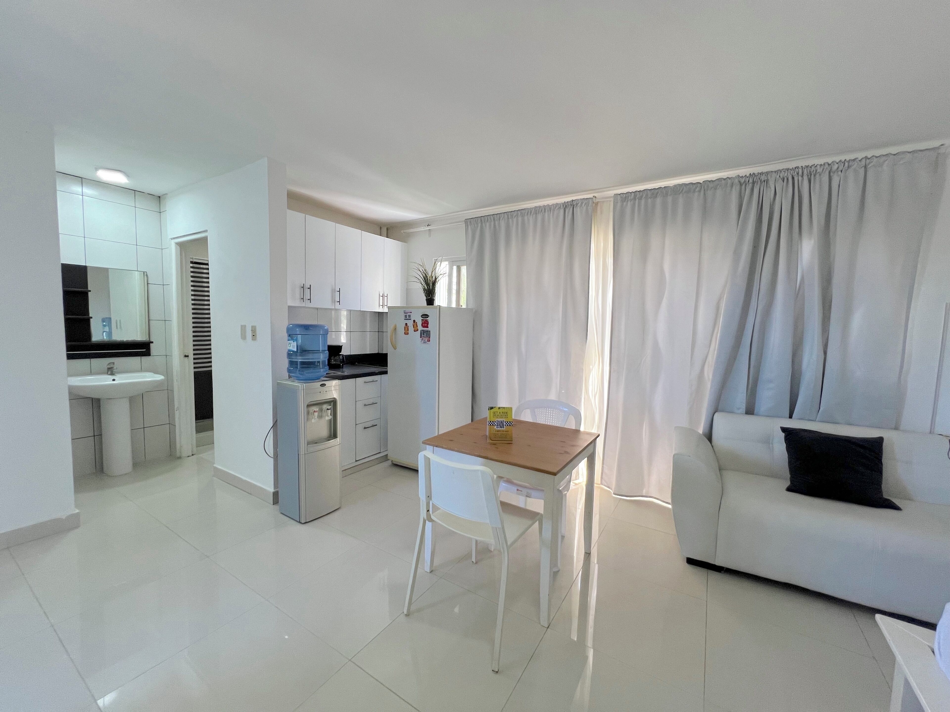 A modern living room with a white sofa and a dining table.