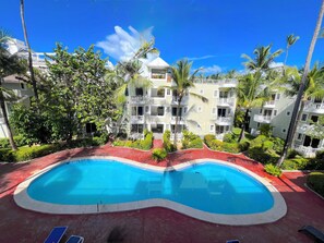Un hotel con piscina, palmeras y un cielo azul despejado.