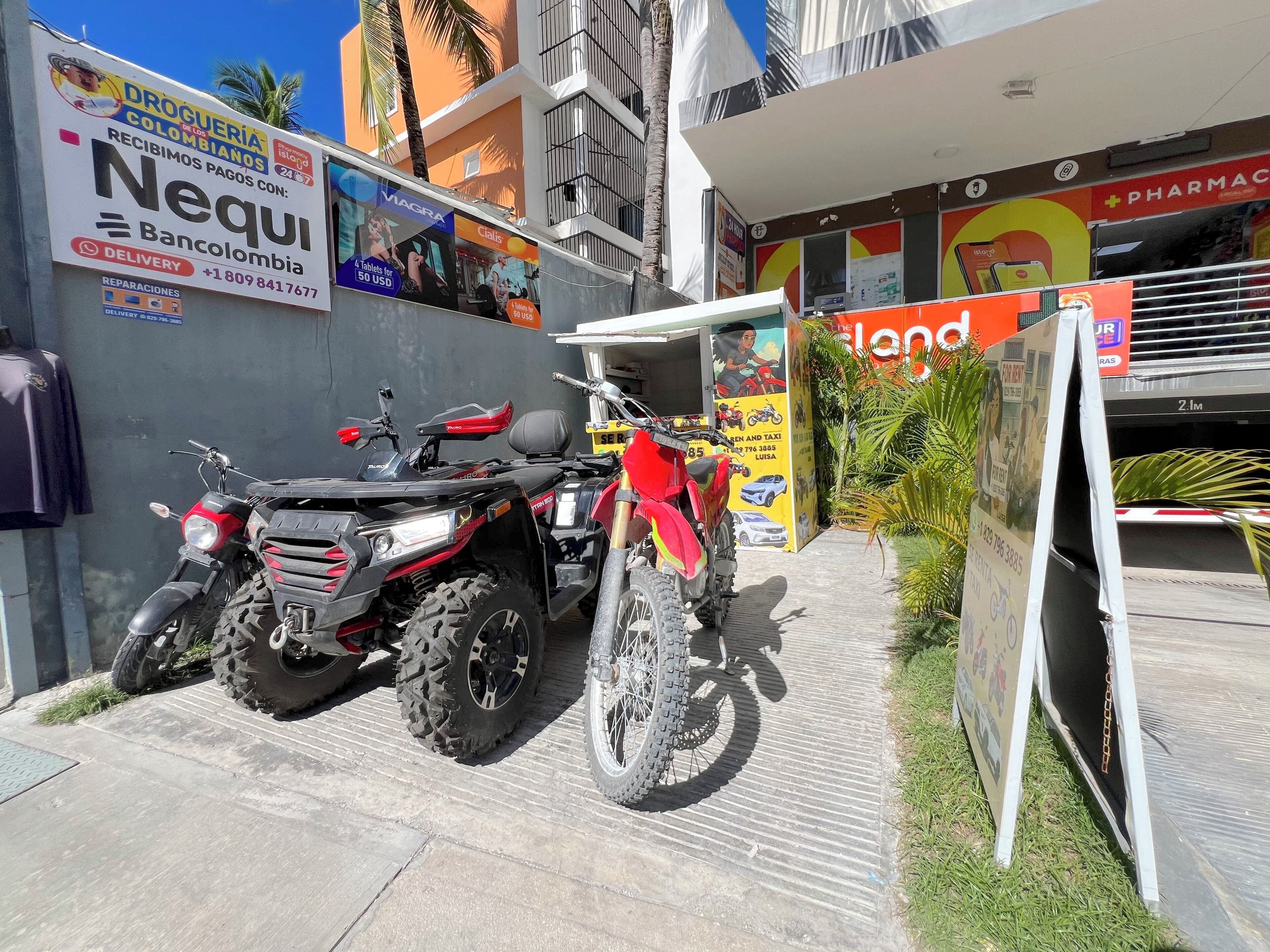Una motocicleta estacionada frente a un edificio con un cartel anunciando una farmacia.