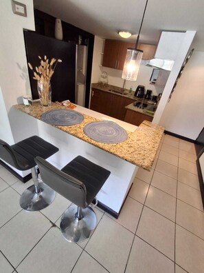 Uma cozinha moderna com bancadas de granito, dois banquetes e uma mesa de jantar.