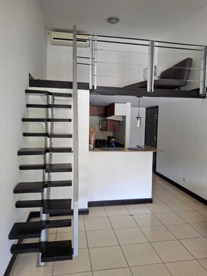 Un appartement moderne doté d’une cuisine centrale, d’une mezzanine et d’un escalier.