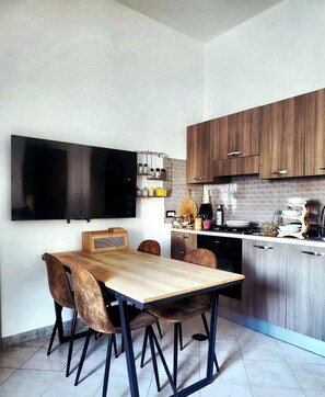 Una cucina moderna con mobili in legno, un tavolo da pranzo con sedie, una TV a incasso e diversi elettrodomestici.
